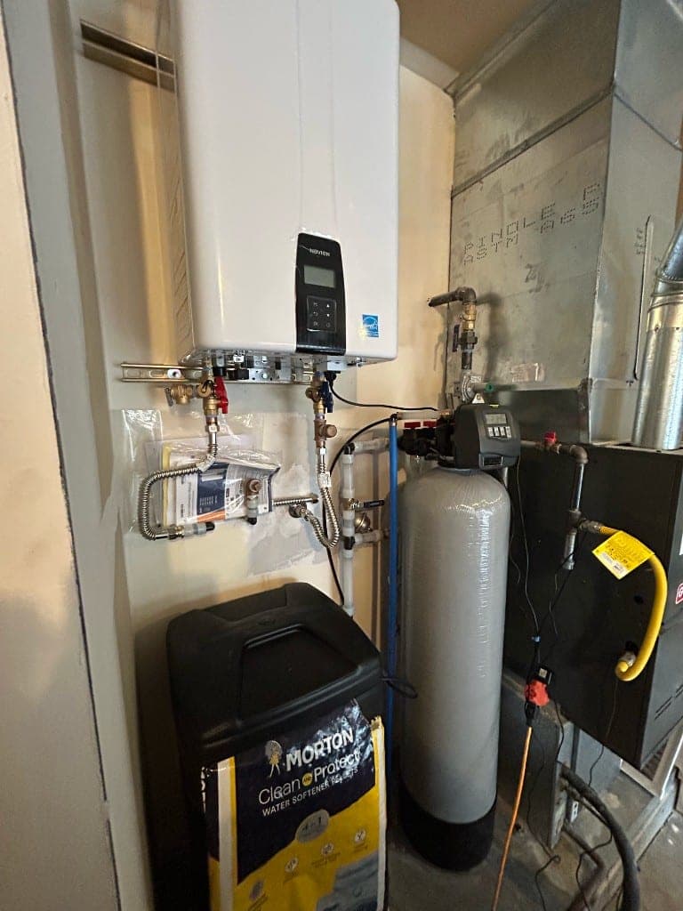 Single Navien tankless water heater installed with a water softener and brine tank in a residential mechanical room