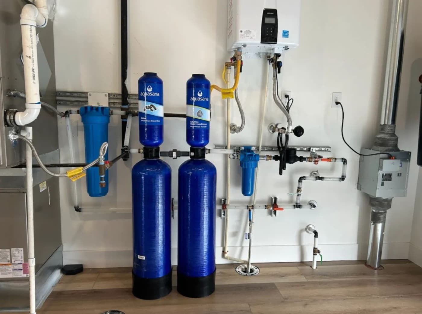 Whole-house water filtration and softener system installed beside a tankless water heater